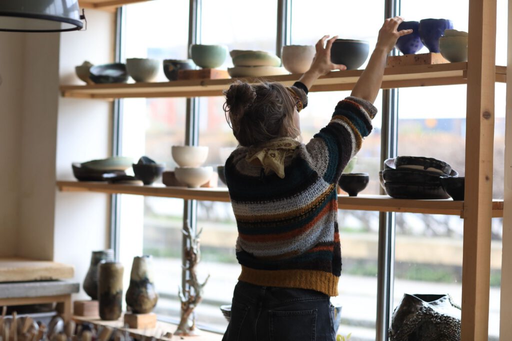 Alice arranging bowls on the studio shelves